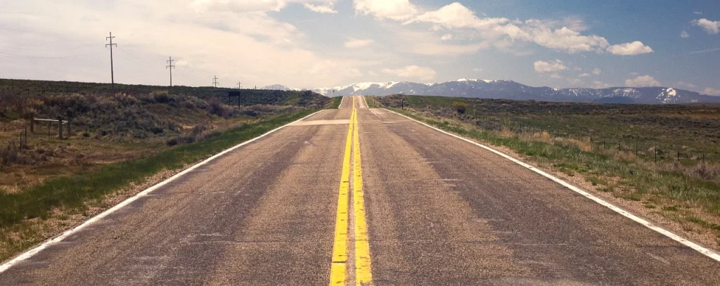 “Professional 401k financial advisor at Reignmakers guiding a client along the path to retirement, represented by a serene road leading into the mountains, symbolizing the journey to achieving financial peace and stability.”